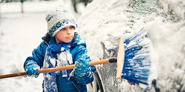 Kind veegt auto sneeuw schoon