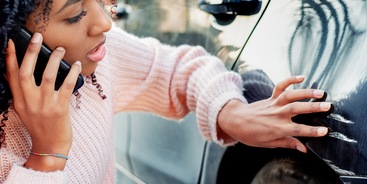 vrouw bekijkt kras op auto