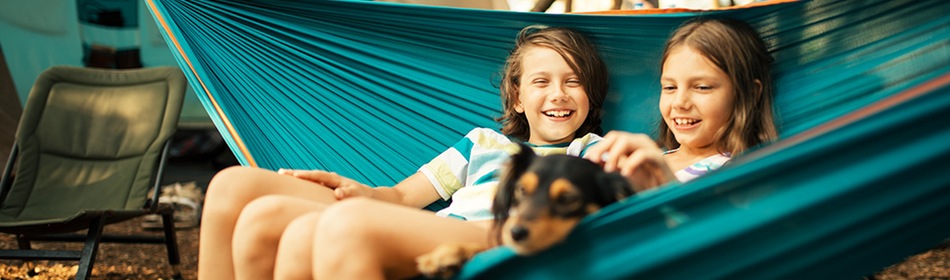 2 kinderen en een hond in hangmat voor de tent