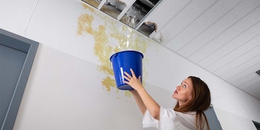 Vrouw met een emmer in haar hand bij waterschade