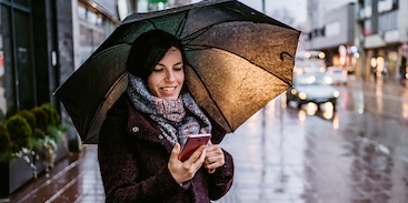 Vrouw met smartphone onder paraplu